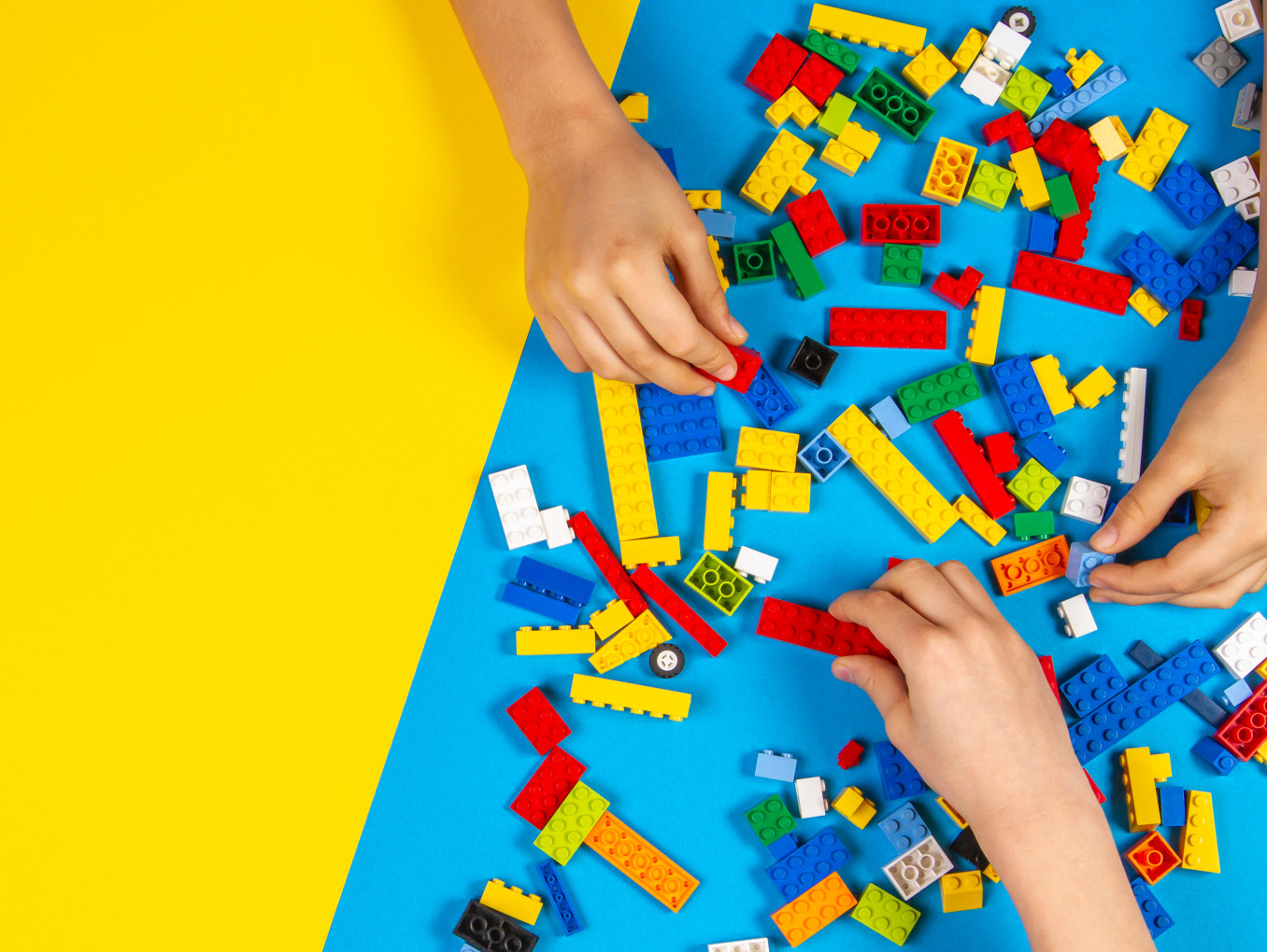 Children's hands playing with colorful Lego bricks