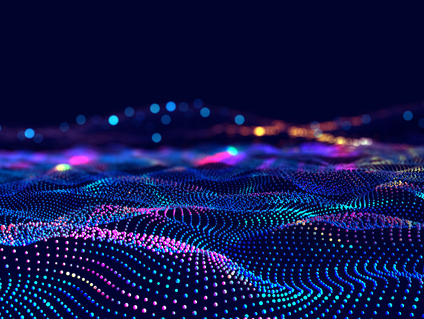 This image displays a digital landscape of multicolored, glowing dots arranged in flowing, wave-like patterns. The dots form a dynamic and futuristic grid, with vibrant hues of blue, pink, purple, and green fading into the background. 
