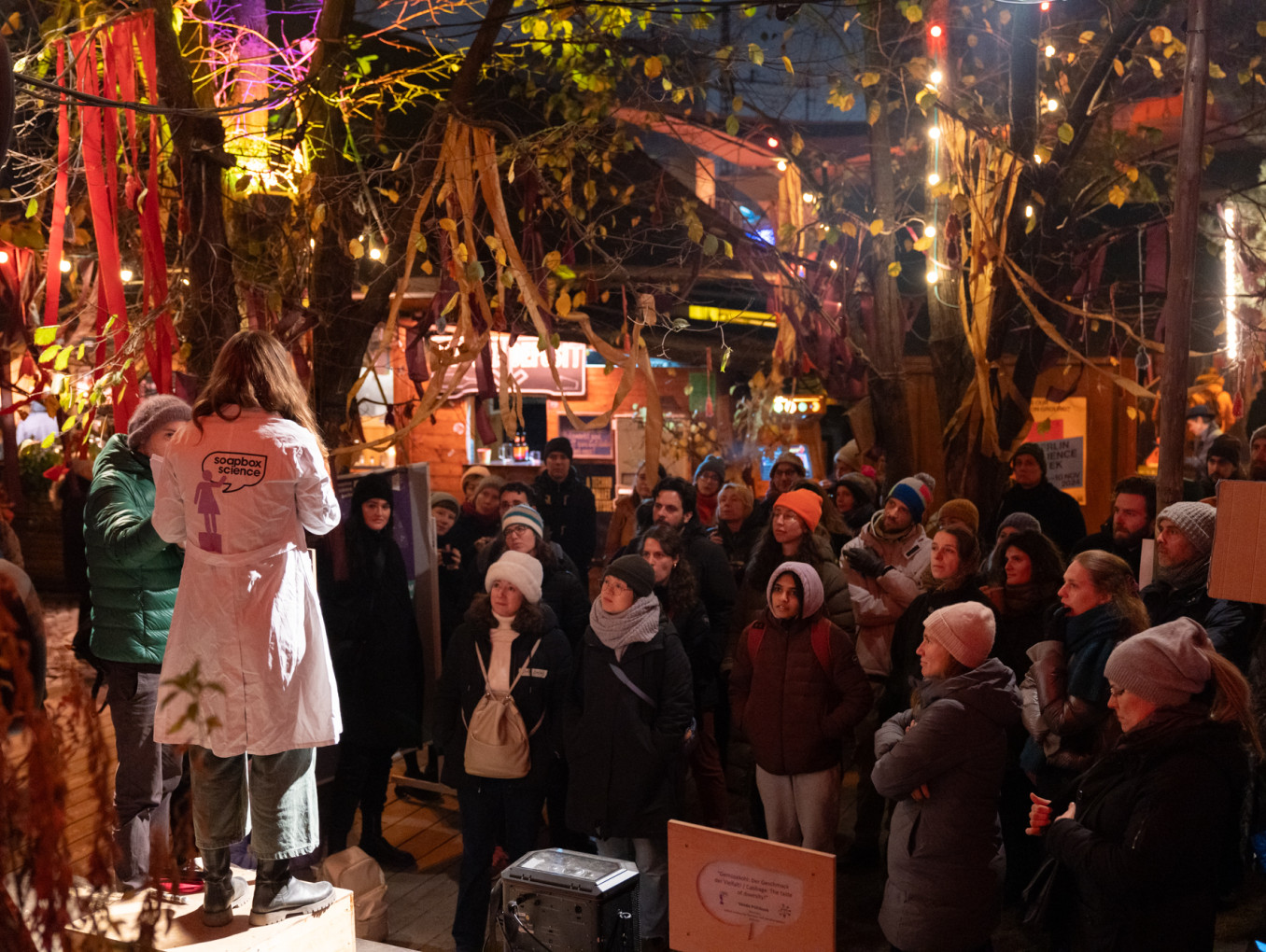 A crowd of people watching a person speaking outside.