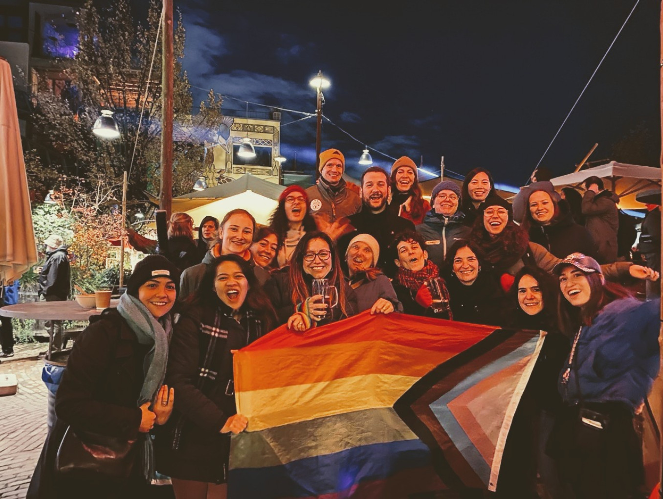Soapbox Science Berlin and LGBTQ+ STEM Berlin teams pose with pride flag at Holzmarkt 25.
