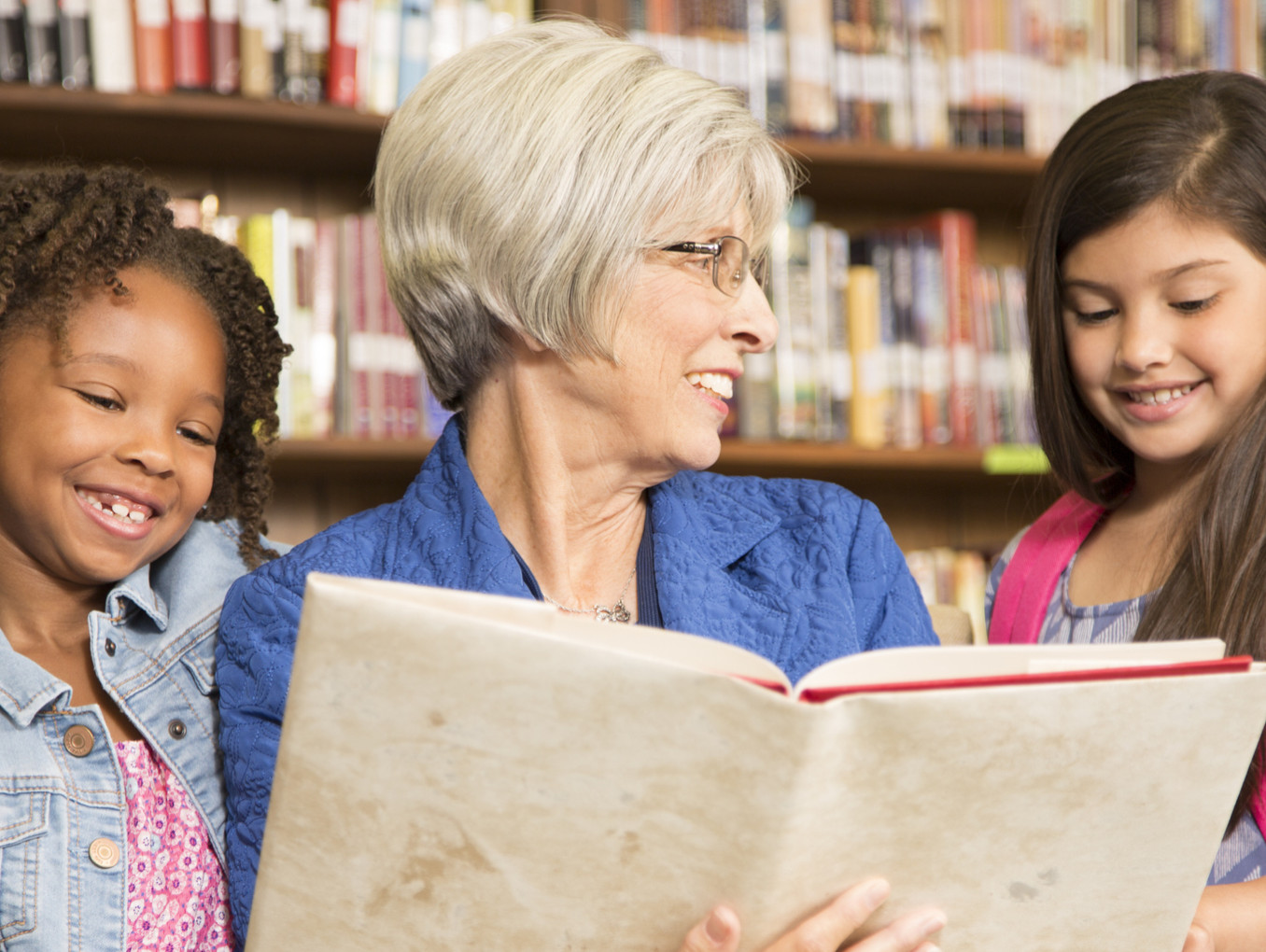 Frau liest zwei Kinder aus einem Buch vor