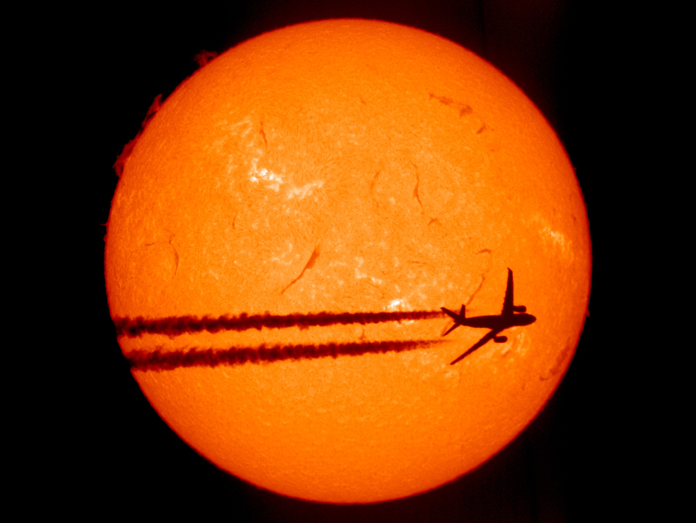 A plane crossing the sun, only its shadow visible
