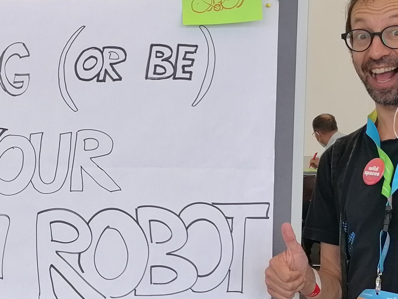 TeeKay neben einem Schild: Bring your own robot !  Bring Deinen eigenen Roboter mit
