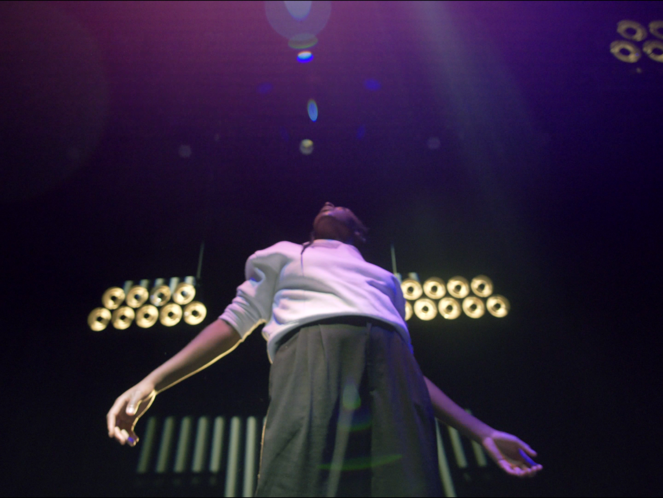  A black person standing on stage looking up