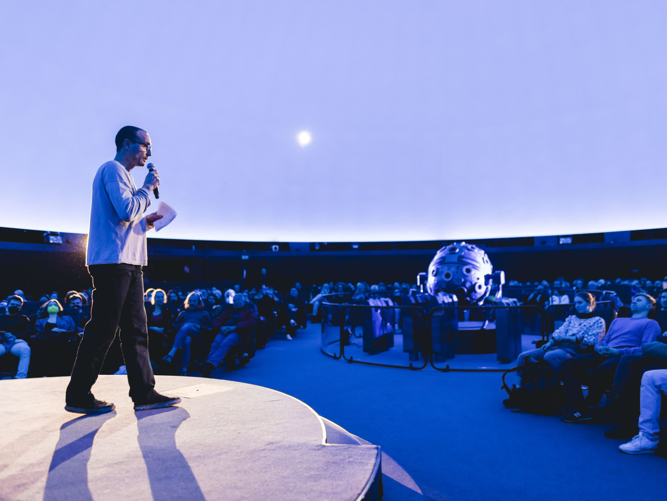 A man stands on stage in the planetarium.