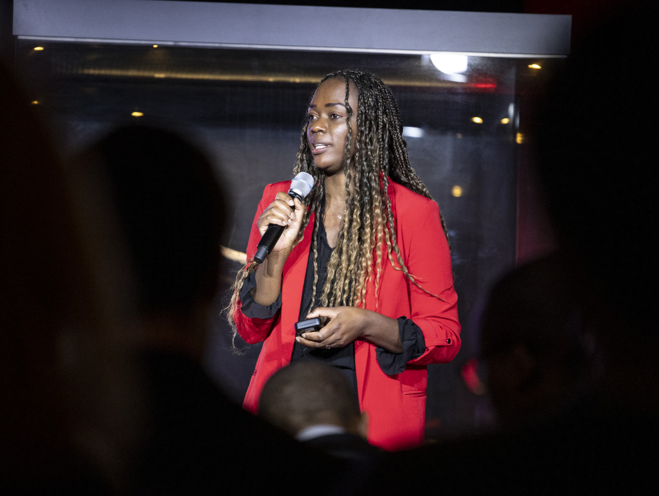 A young woman stands in the middle of the image with a microphone. 