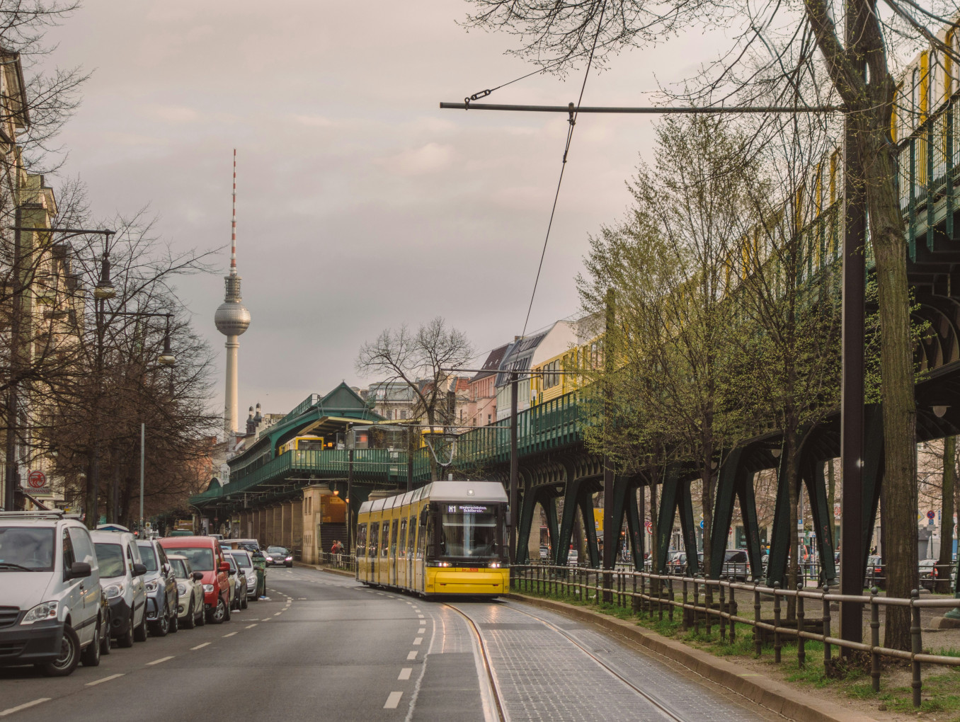 A tram drives through Berlin with the TV tower in the back. 