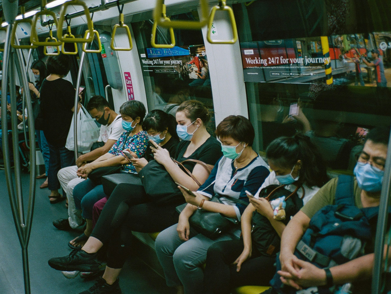 A group of people in public transport stare at their phones. 