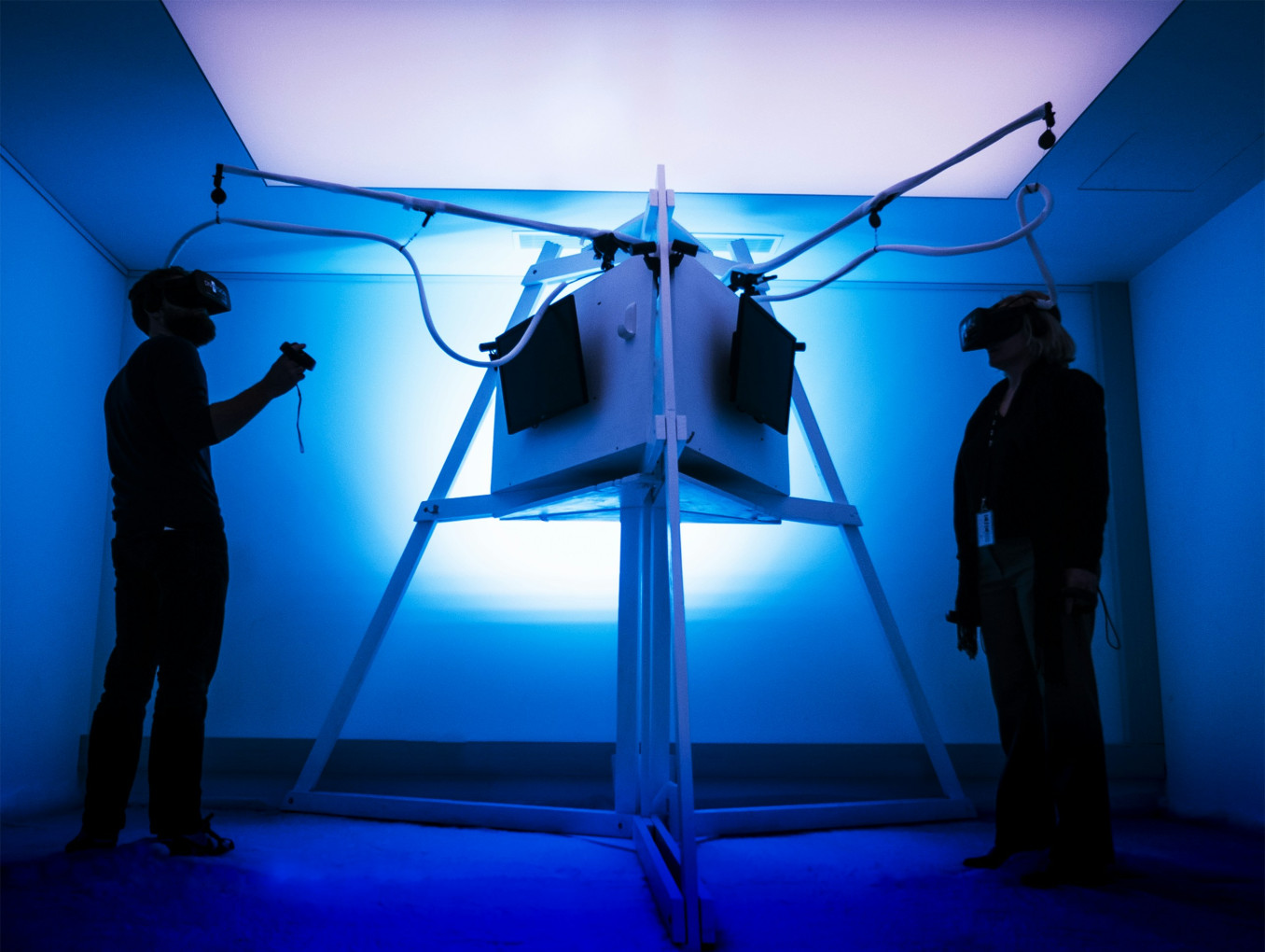 Two people with VR glasses on opposite ends of a machine. 