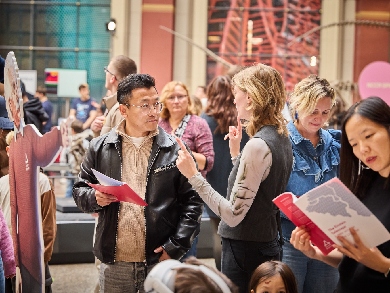 A woman explains something to man with a brochure in a museum.