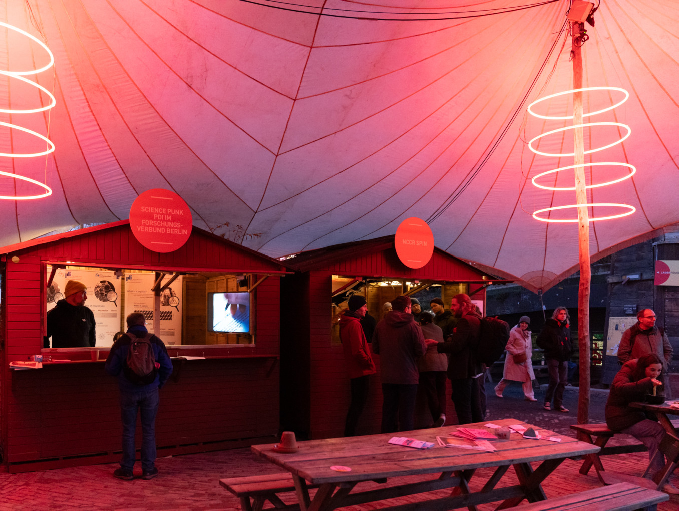 People stand outside of booths in a festival tent.