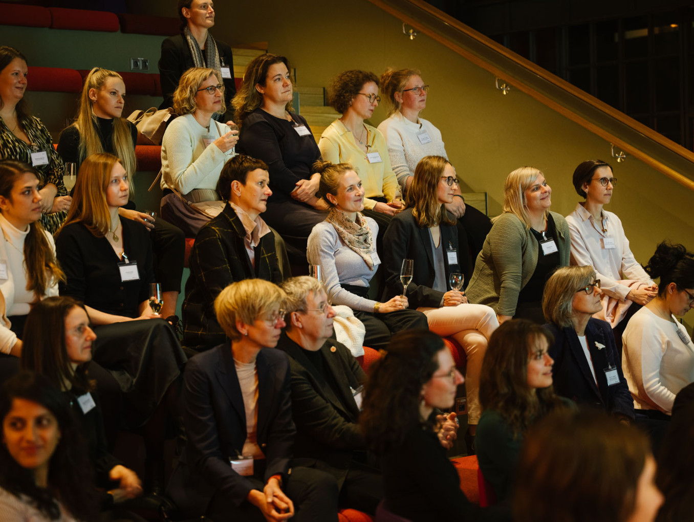 A attentive crowd of women watching from  a seating area.