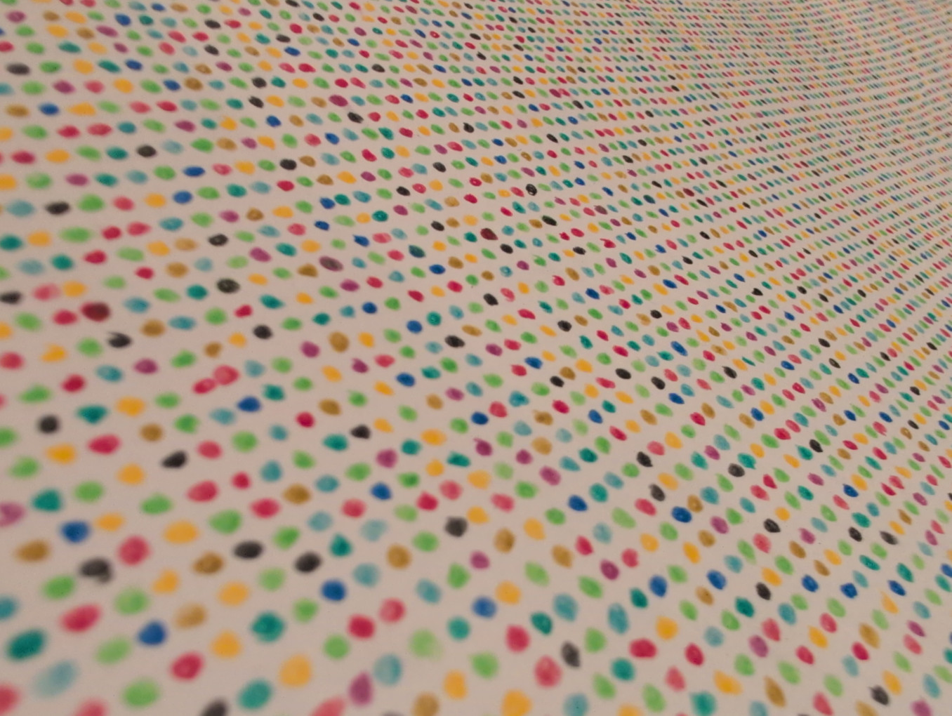 A close-up of a pattern made of many small, colorful dots arranged in rows on a white background.