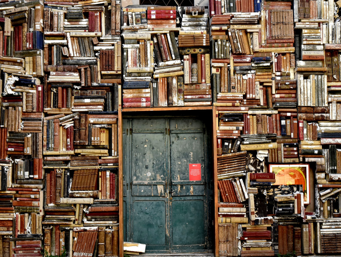 wall with door and bookshelves crammed with books 