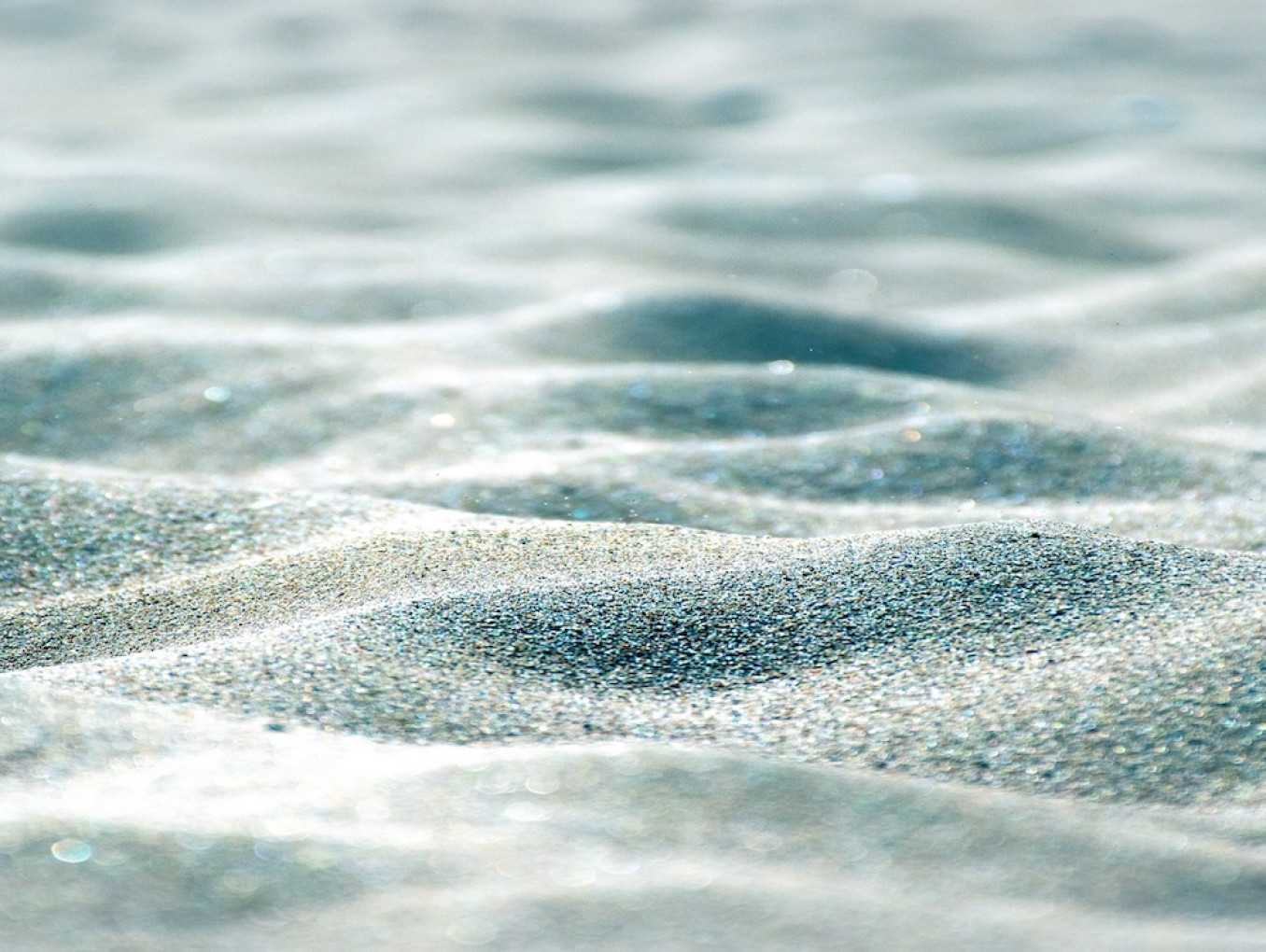 Close-up view of rippled sand with soft light and shadows.