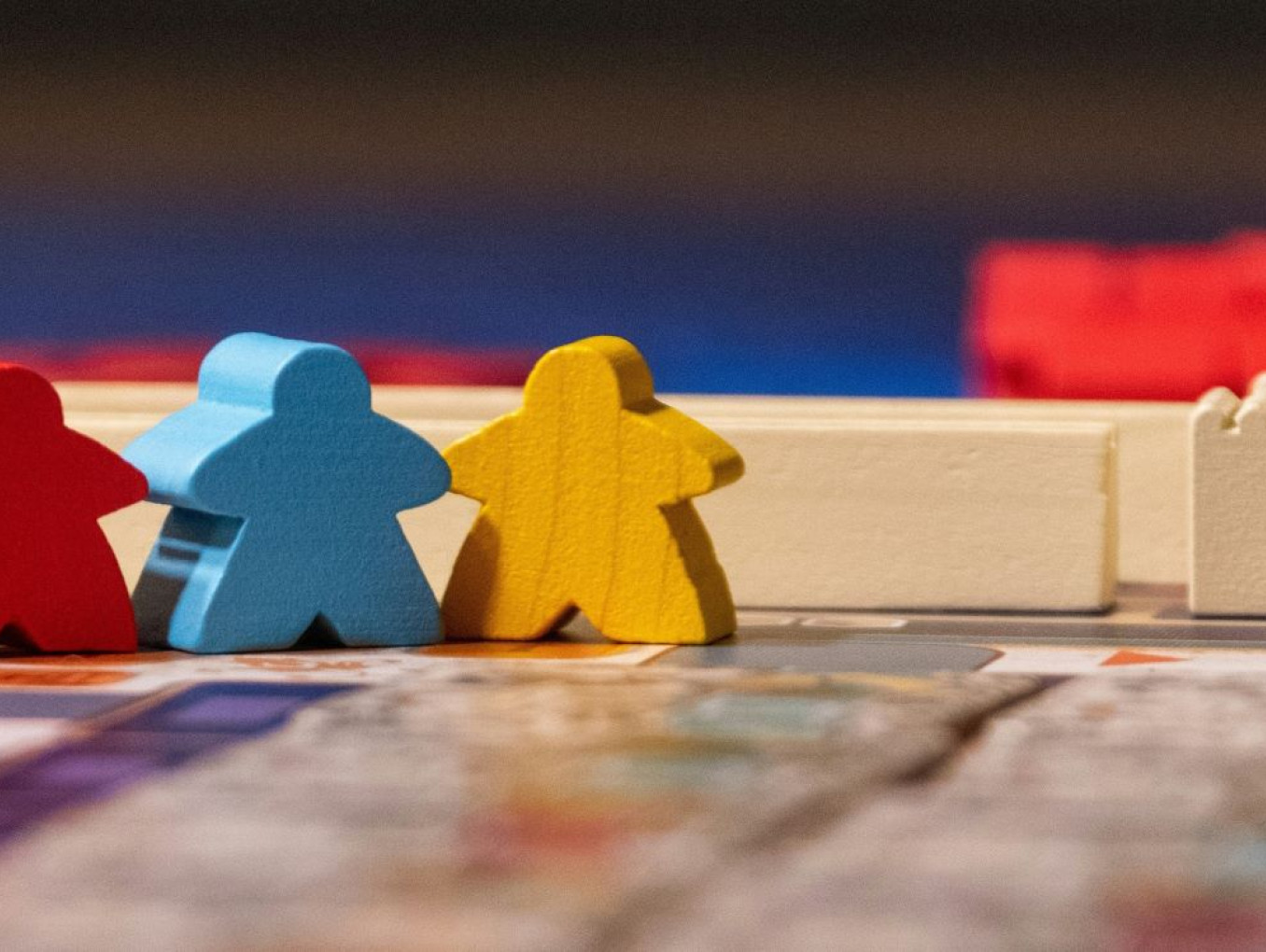 Image of board game with wooden player pieces in red, blue and yellow
