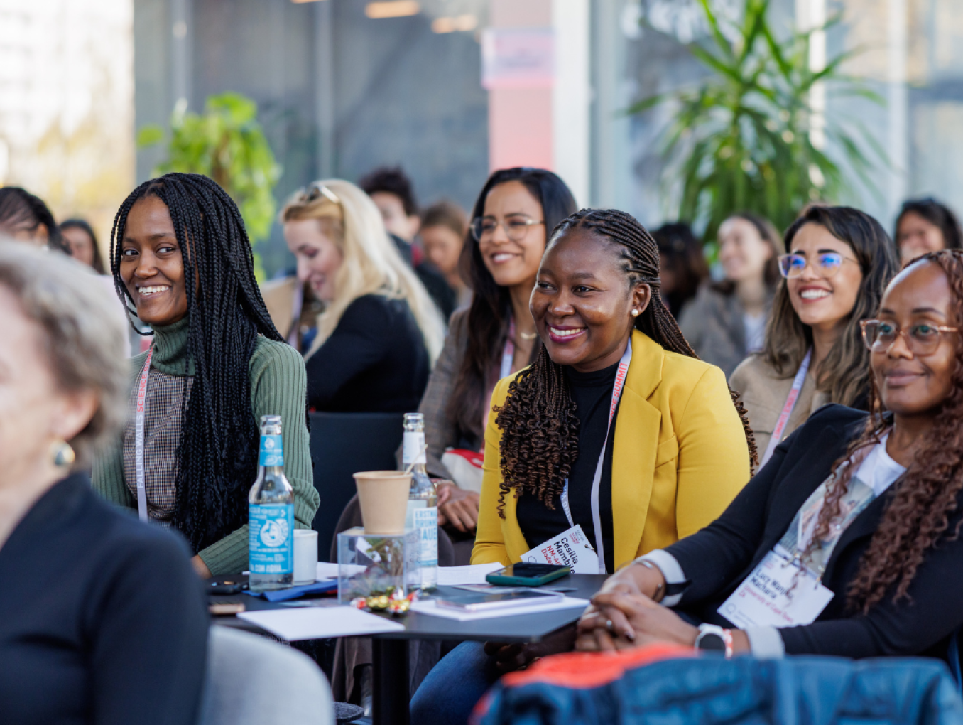 A group of women are sitting in the audience, smiling, looking at the speaker out of frame.