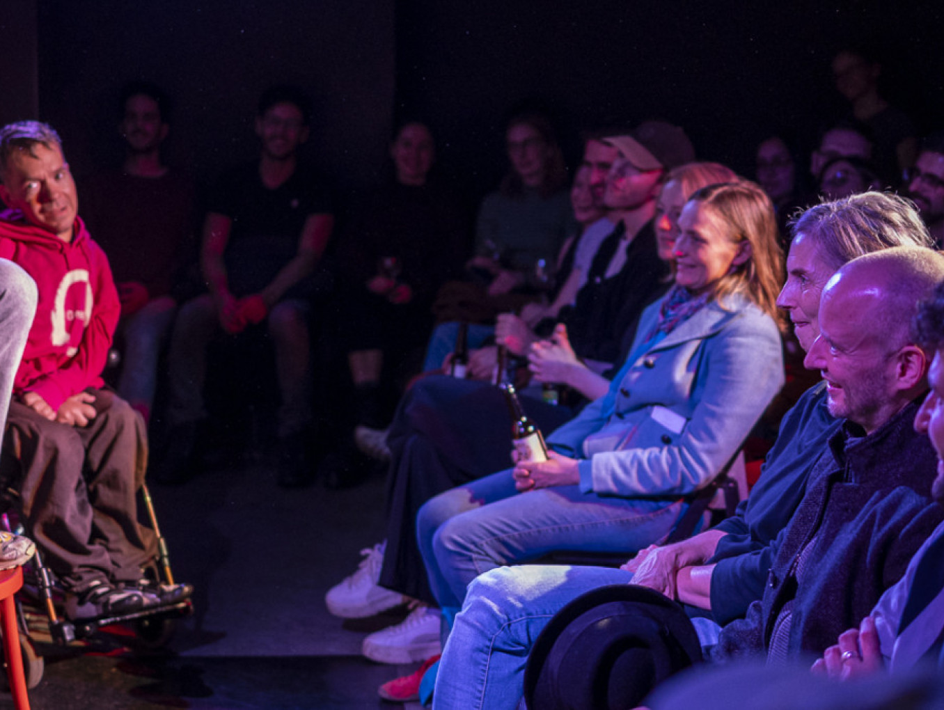 Three performers impersonate birds on stage with audience laughing.
