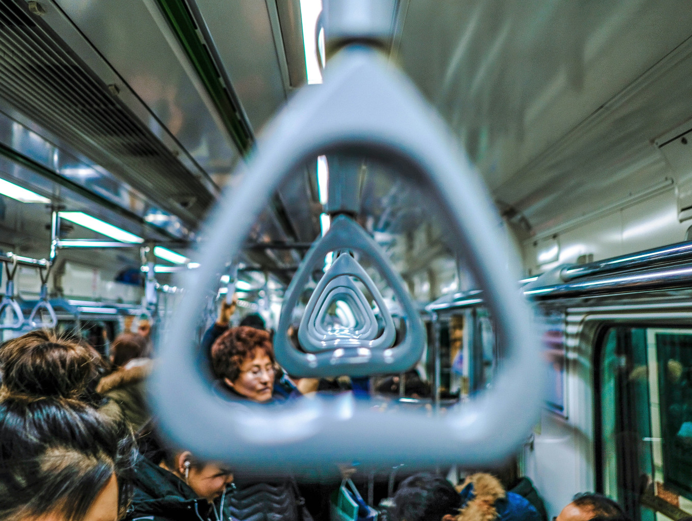 A subway handle in a crowded subway car