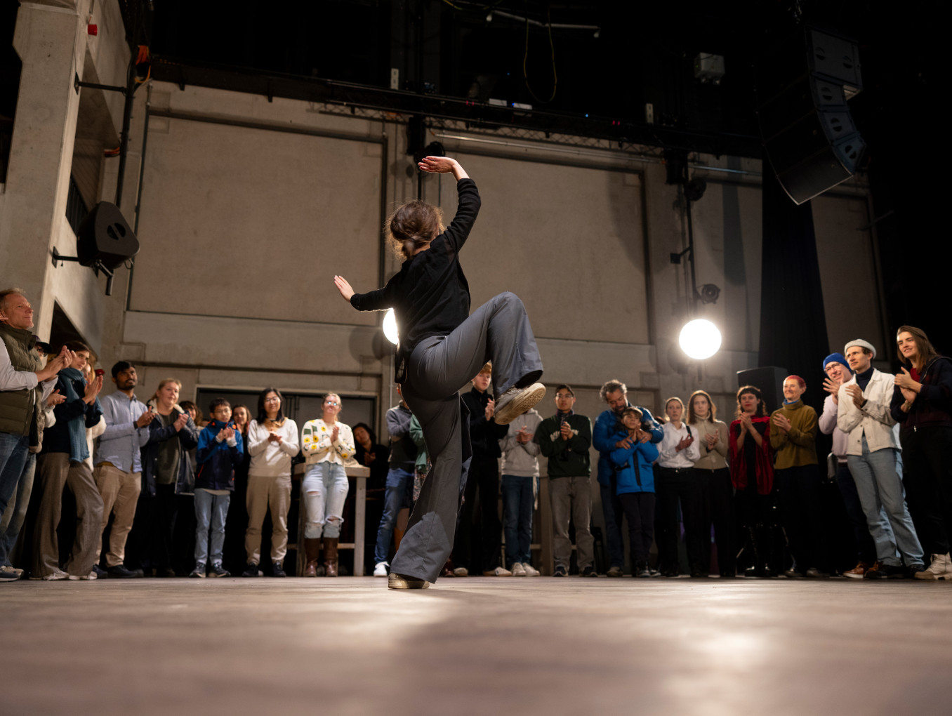 A woman dances in front of a crowd of people.