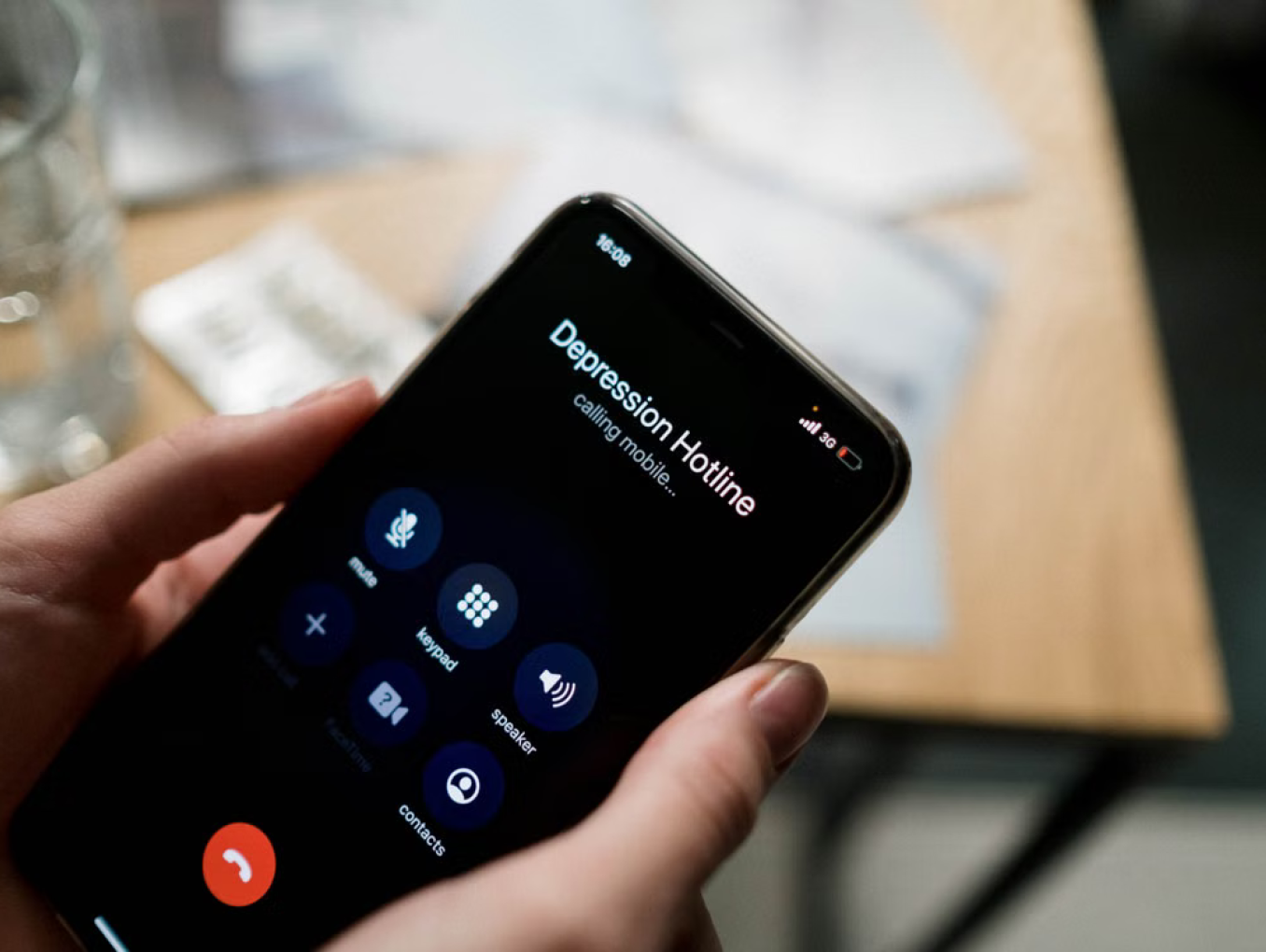 Hands holding a smartphone. The screen shows an outgoing call to a "depression hotline".