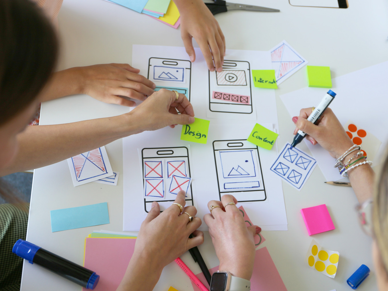 Drei Personen arbeiten an einen Papier-Prototypen für eine mobile Anwendung. 
