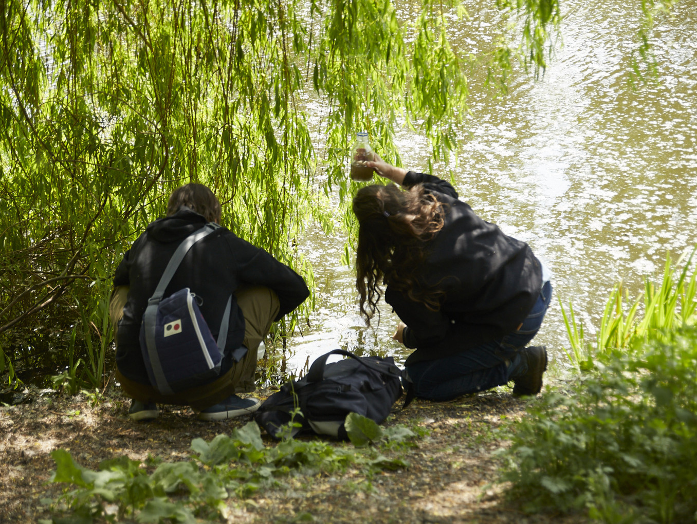 Two people collective water samples from a pond