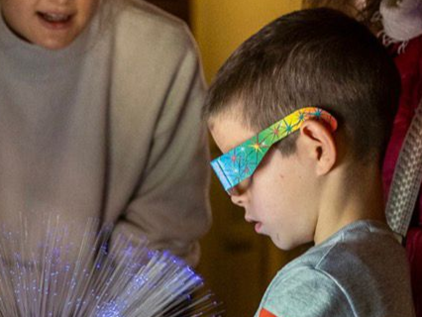 A boy fascinated by viewing a fiber light source through polarizing filter goggles