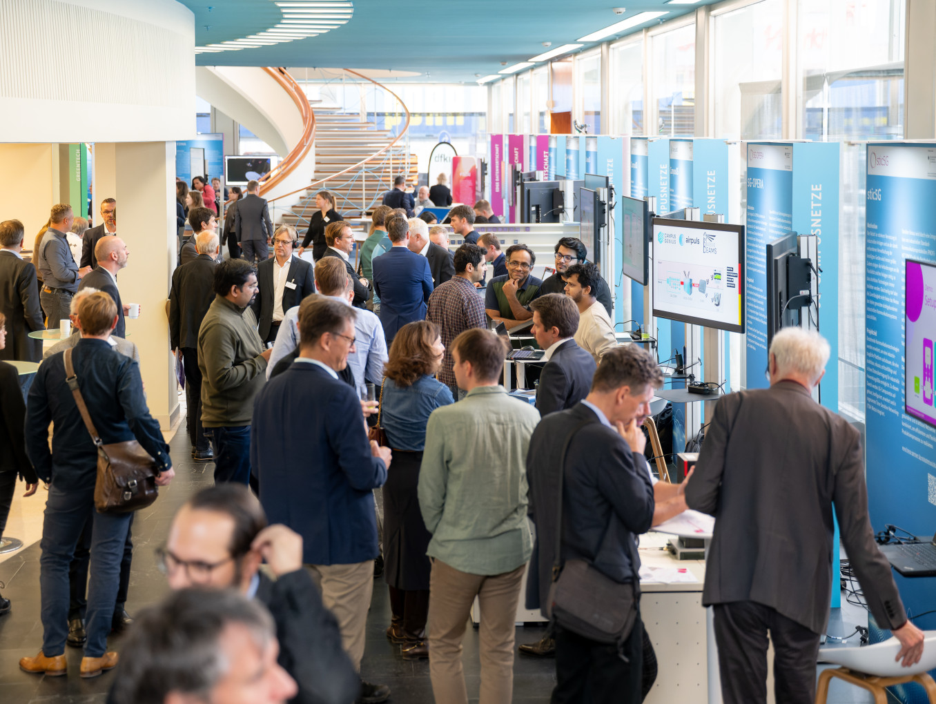 Besucherinnen und Besucher tauschen sich im Ausstellungsbereich der Tage der digitalen Technologien aus.