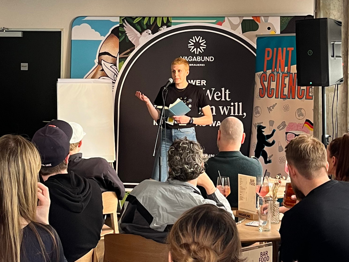Scientist gives talk in front of crowd in a bar.