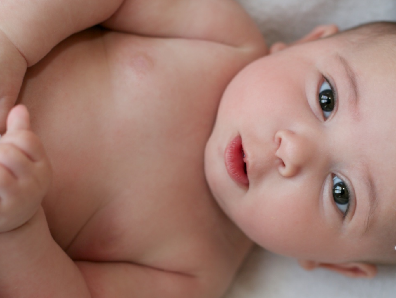 Ein Baby wurde in  ein Handtuch gewickelt und schaut in die Kamera.