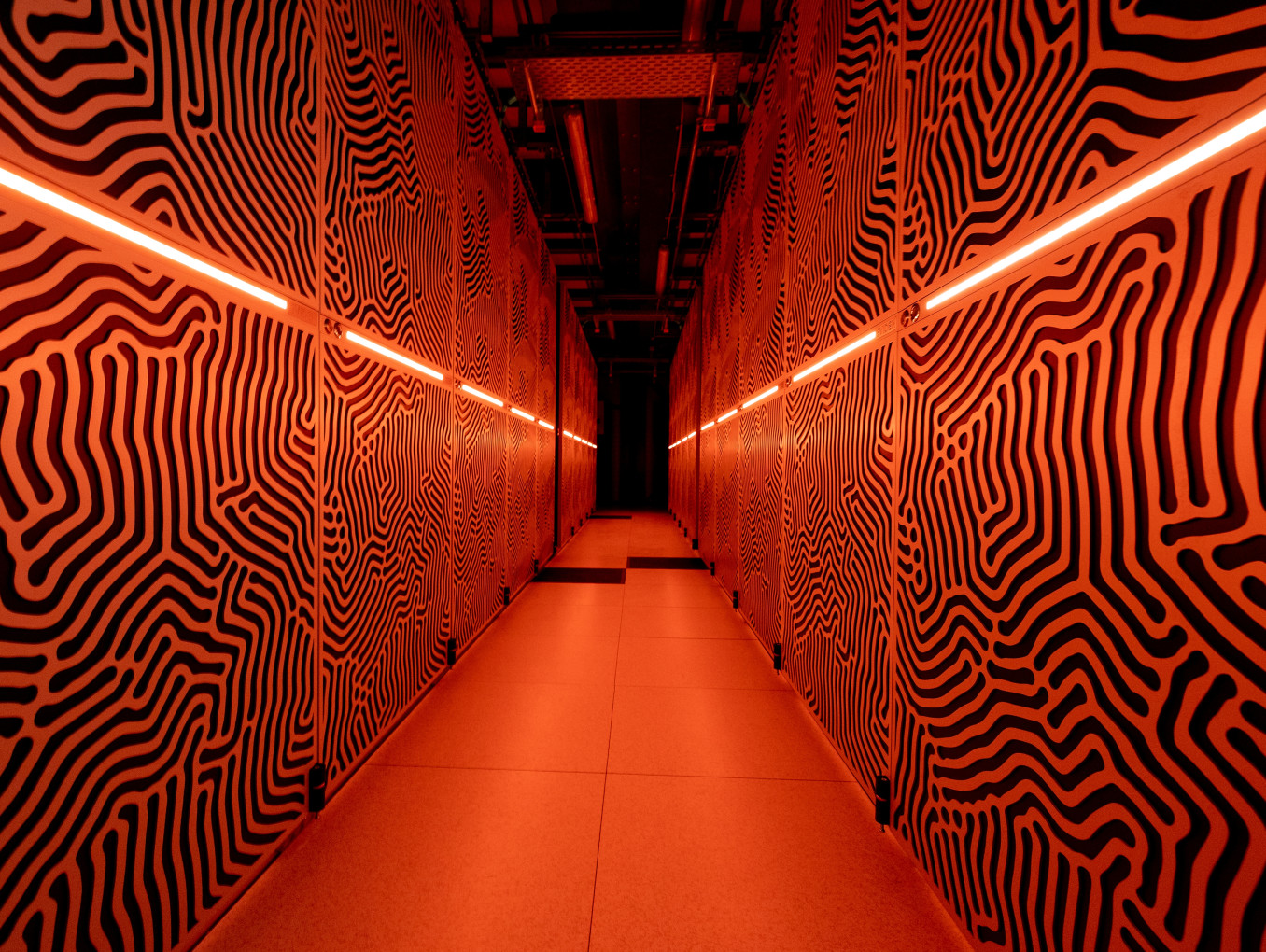 Die Rechnerschränke unseres Supercomputers „JUPITER” sind in orangem Licht getaucht.
