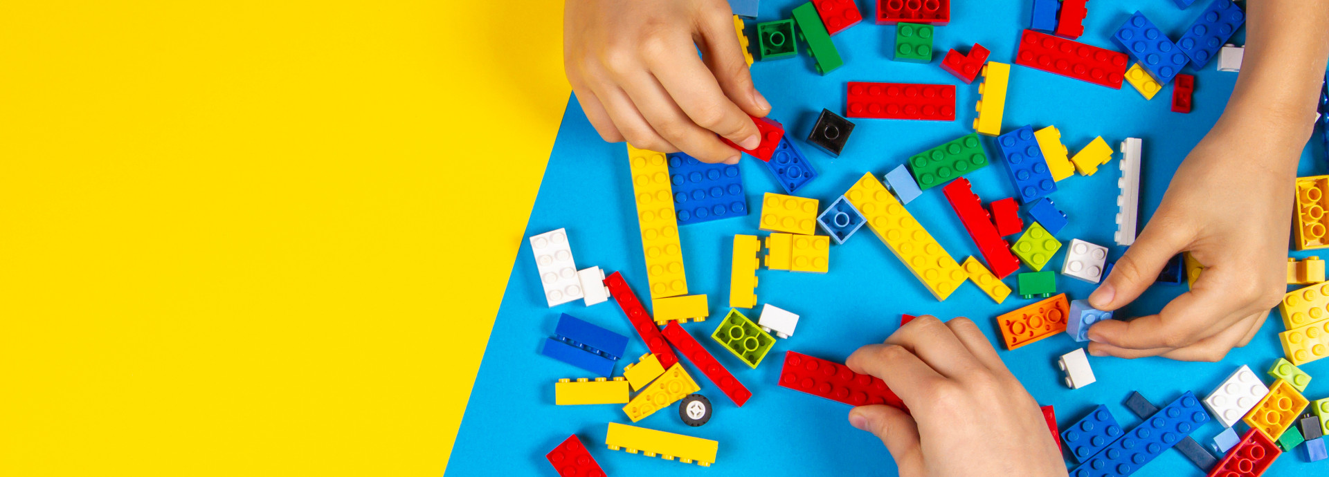 Children's hands playing with colorful Lego bricks