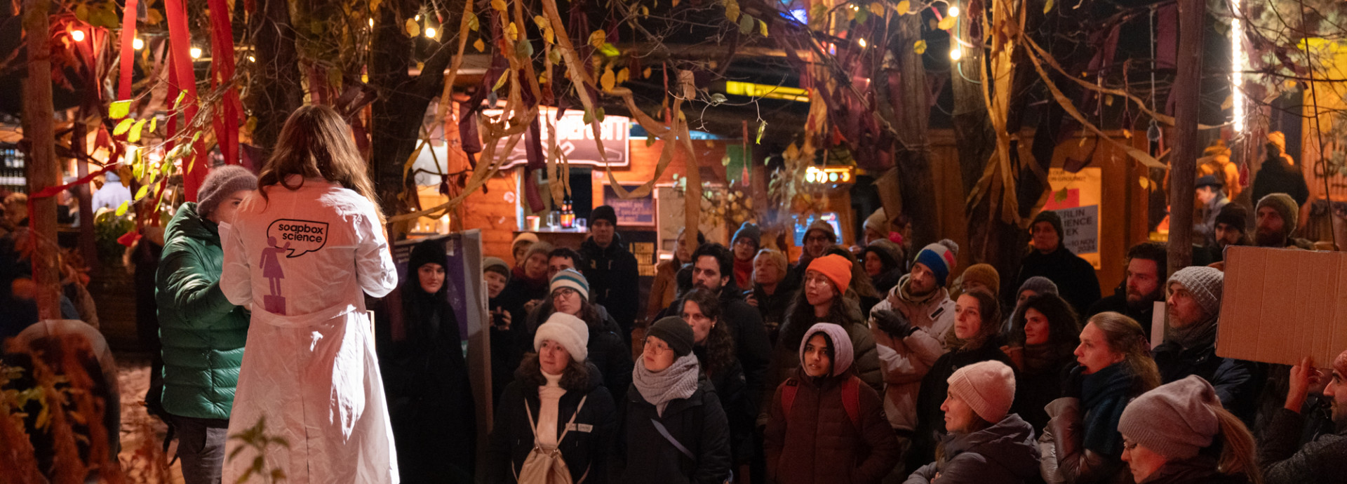 A crowd of people watching a person speaking outside.