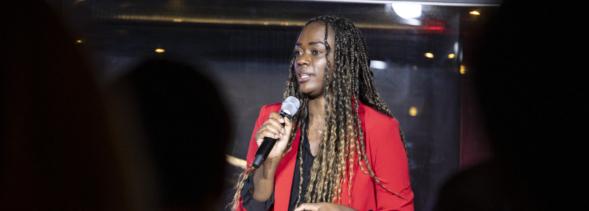 A young woman stands in the middle of the image with a microphone. 