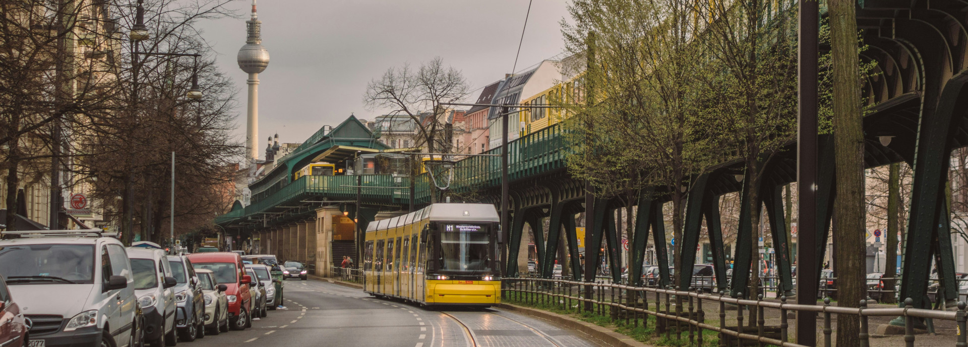 A tram drives through Berlin with the TV tower in the back. 