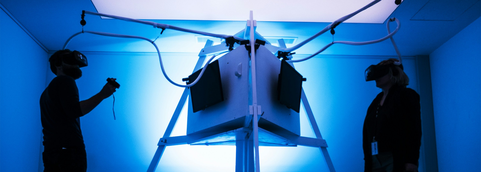 Two people with VR glasses on opposite ends of a machine. 