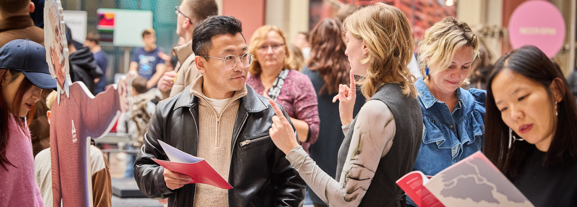 A woman explains something to man with a brochure in a museum.