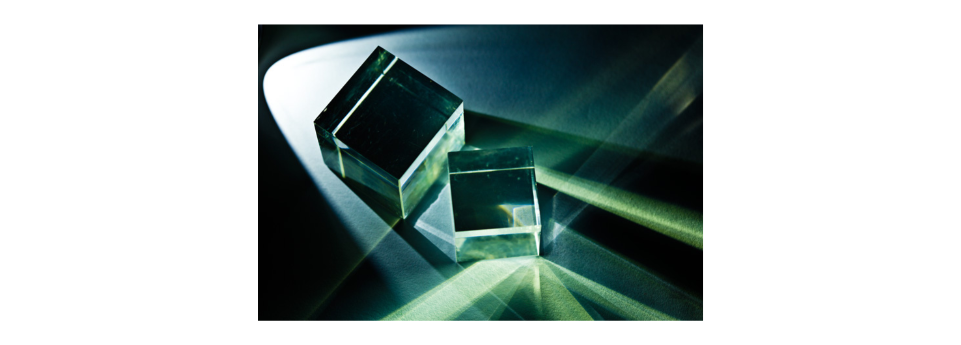 Zwei Glaskuben brechen das Licht und erzeugen ein Spiel aus Schatten und grün-bläulichen Lichtstrahlen.