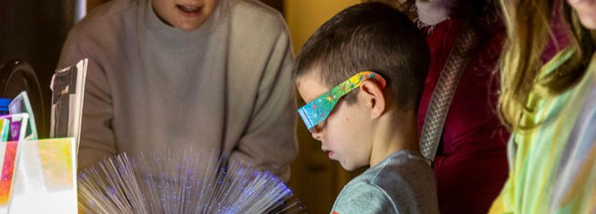 A boy with refractive glasses staring into a fiber guided light source.