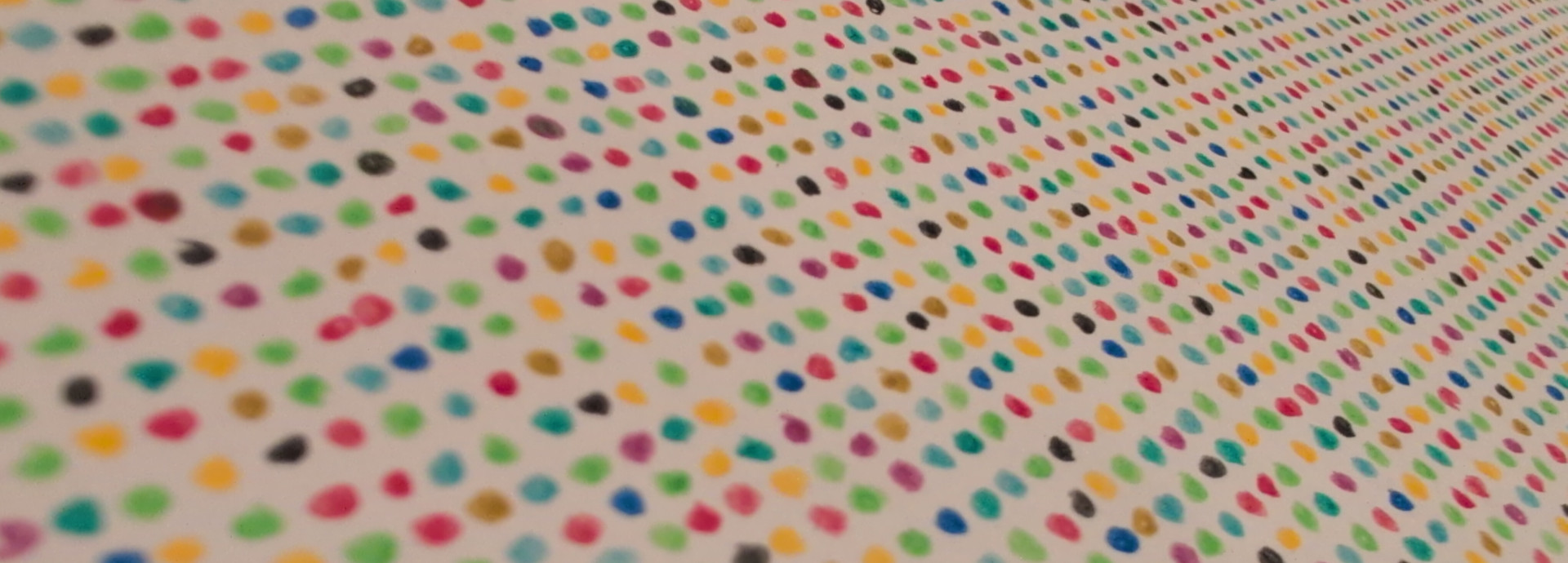 A close-up of a pattern made of many small, colorful dots arranged in rows on a white background.