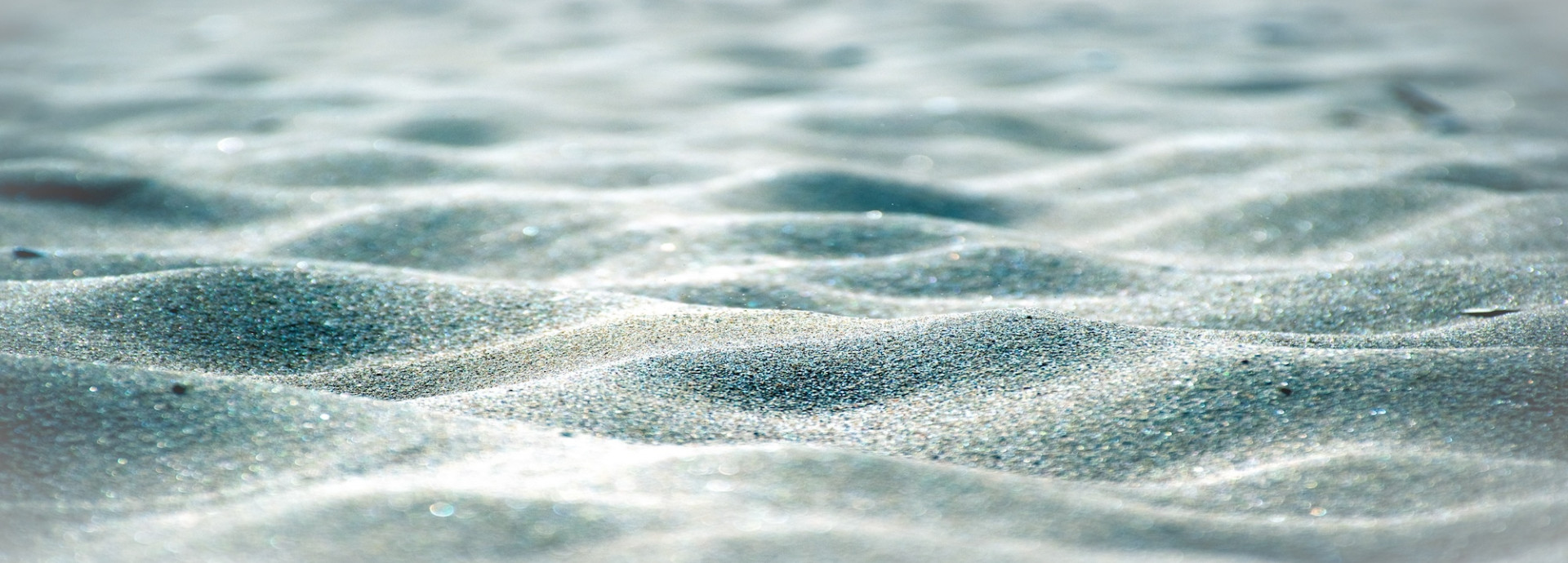Close-up view of rippled sand with soft light and shadows.