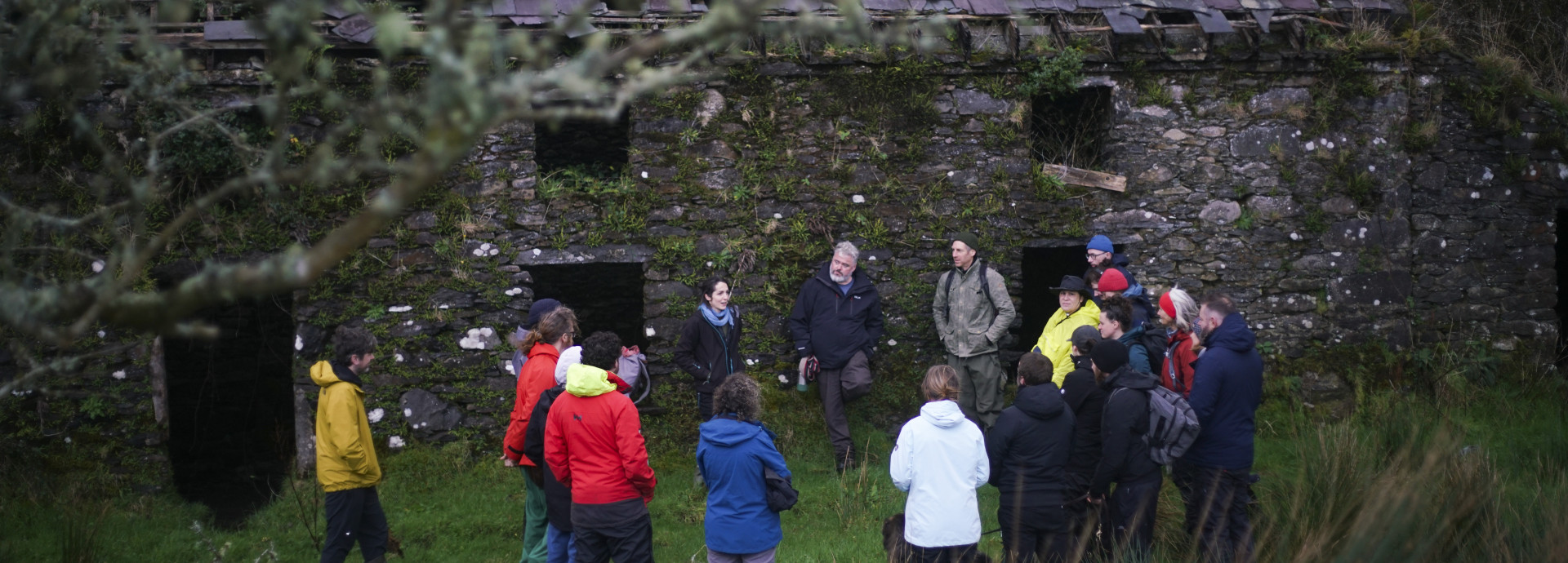 Image of a group standing outside an old stone cottage in the Irish uplands