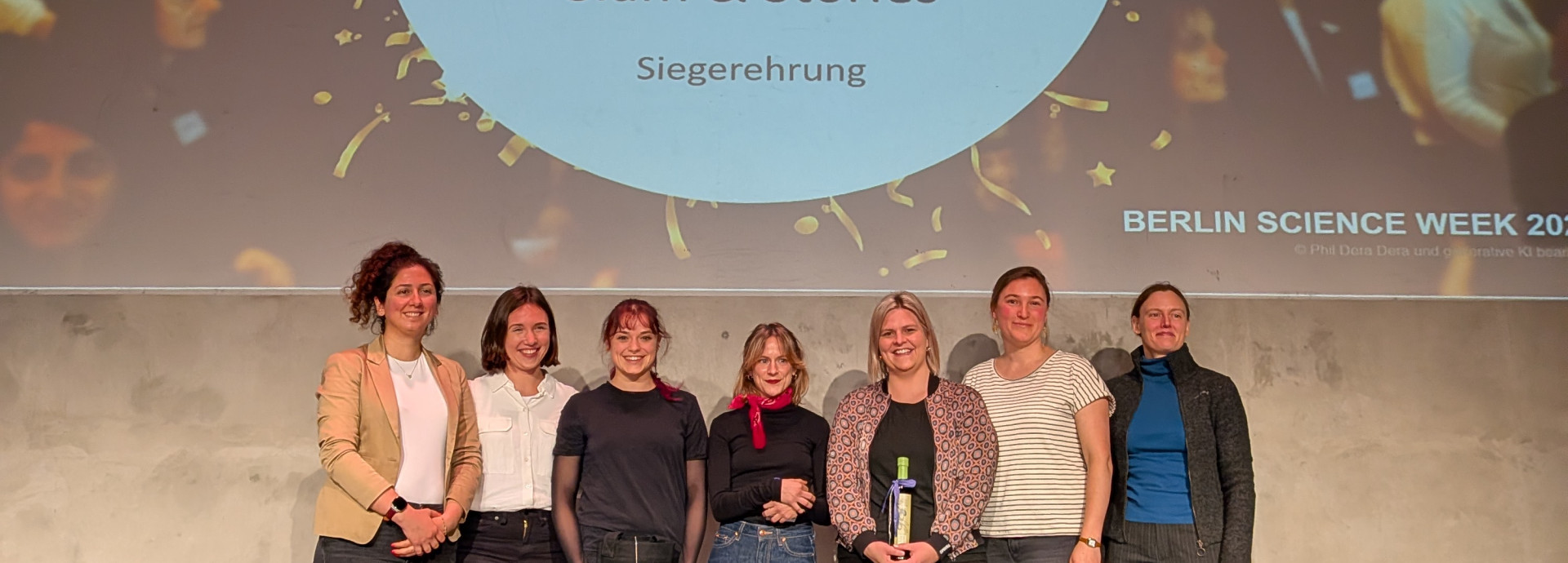 Gruppenfoto von sieben Frauen auf einer Bühne vor einer Leinwand mit dem Schriftzug „Zia Women in Science Slam & Stories – Siegerehrung“.
