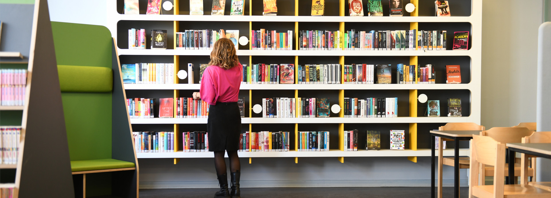 A woman in a library picking a book
