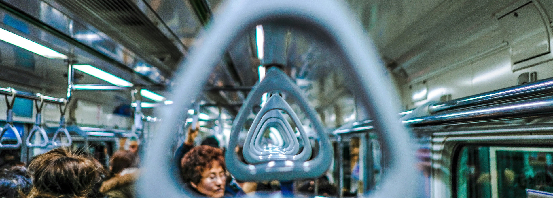 A subway handle in a crowded subway car
