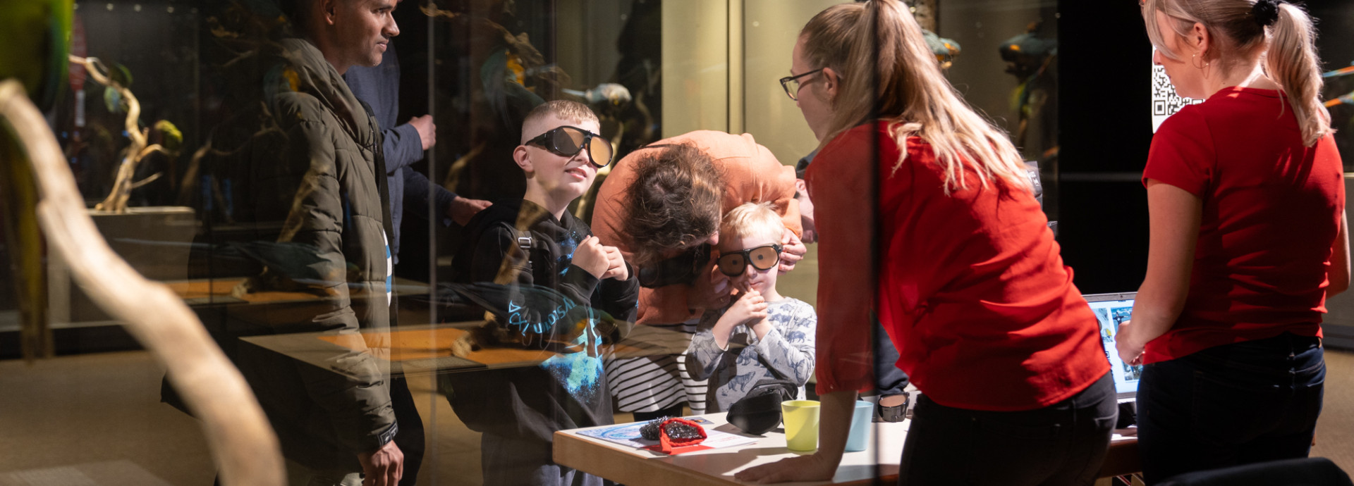 Two children and various adults wear glasses at an exhibition booth.