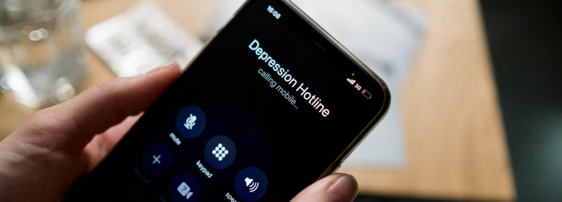 Hands holding a smartphone. The screen shows an outgoing call to a "depression hotline".