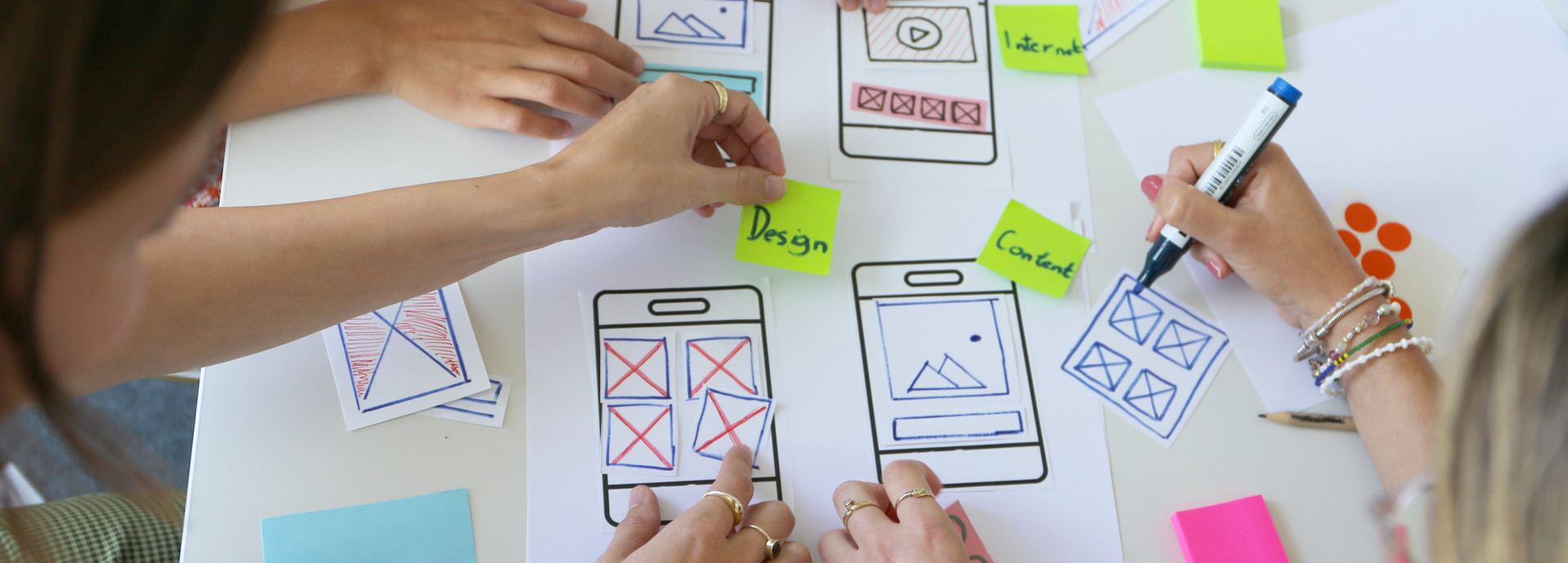 Drei Personen arbeiten an einen Papier-Prototypen für eine mobile Anwendung. 