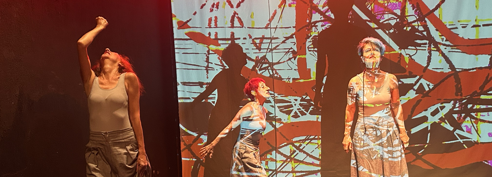 Three performers in front of an abstract video projection